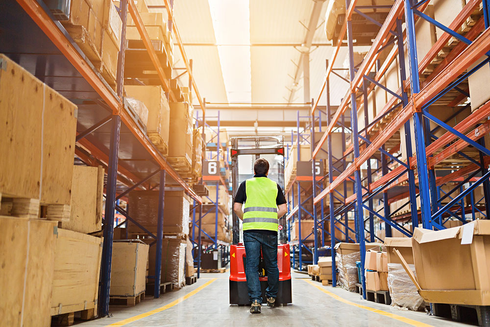 worker in warehouse pushing cart, safe workplace